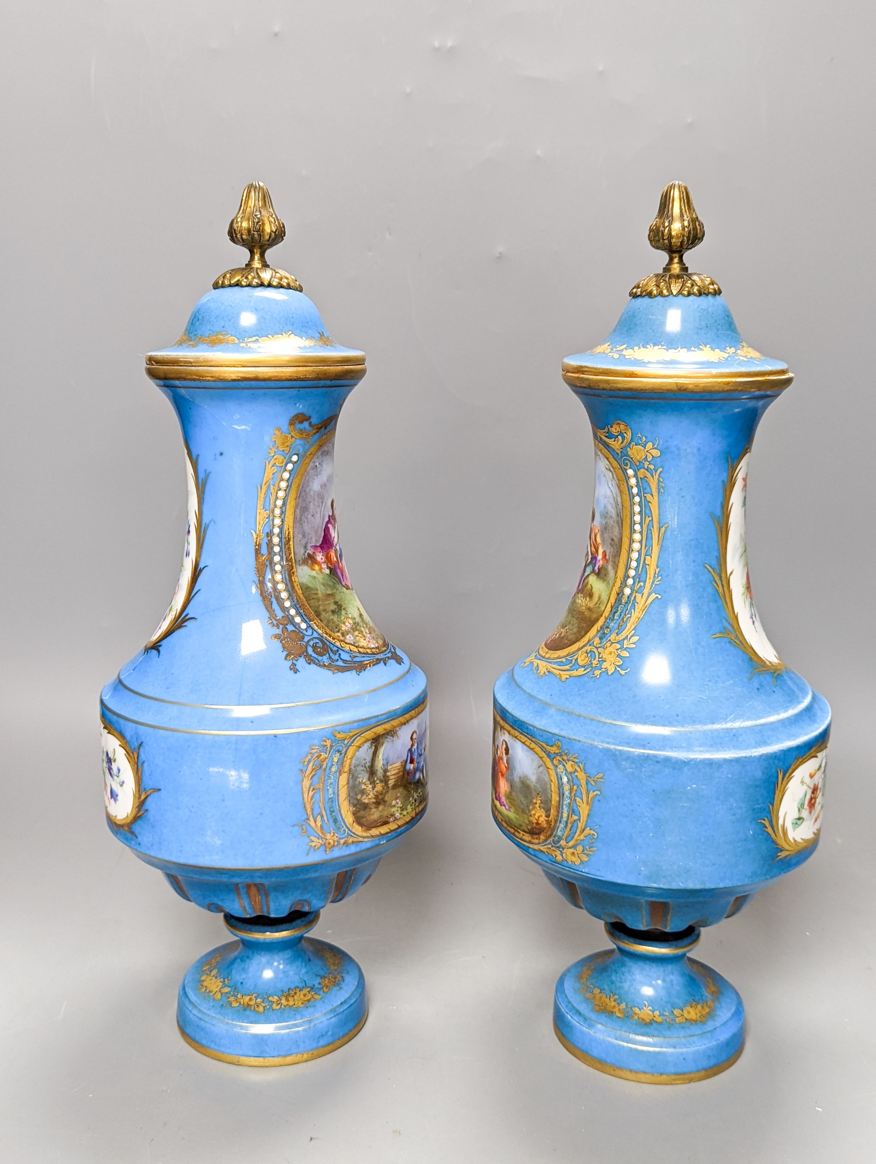 A pair of Sevres style porcelain bleu celeste ground vases and covers, 34cm